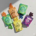 Higher Fire Shatter Gummy Cubes 2500mg pouches in multiple flavours arranged on a light stone surface.